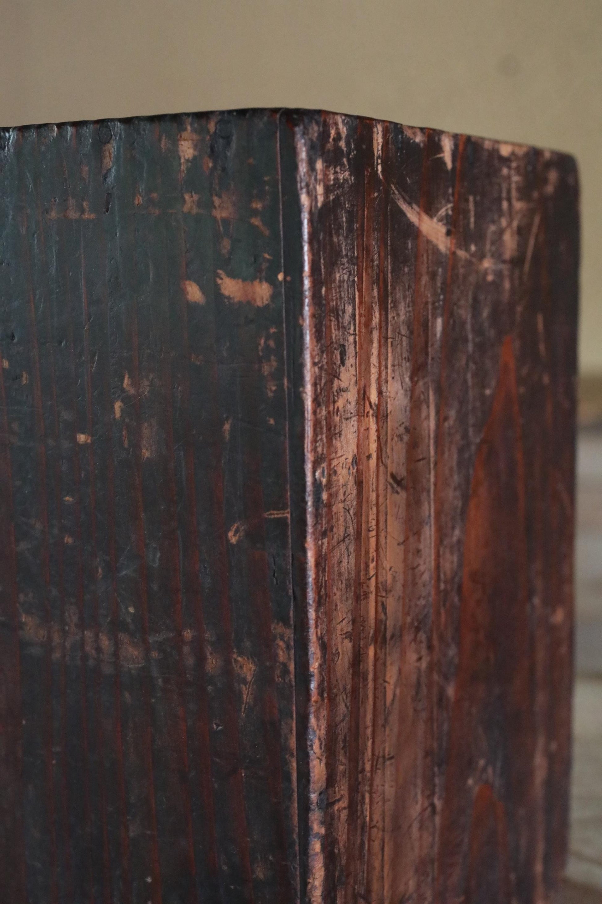 a close-up view of a dark wooden surface with visible grain and texture, giving it a rustic and aged appearance.