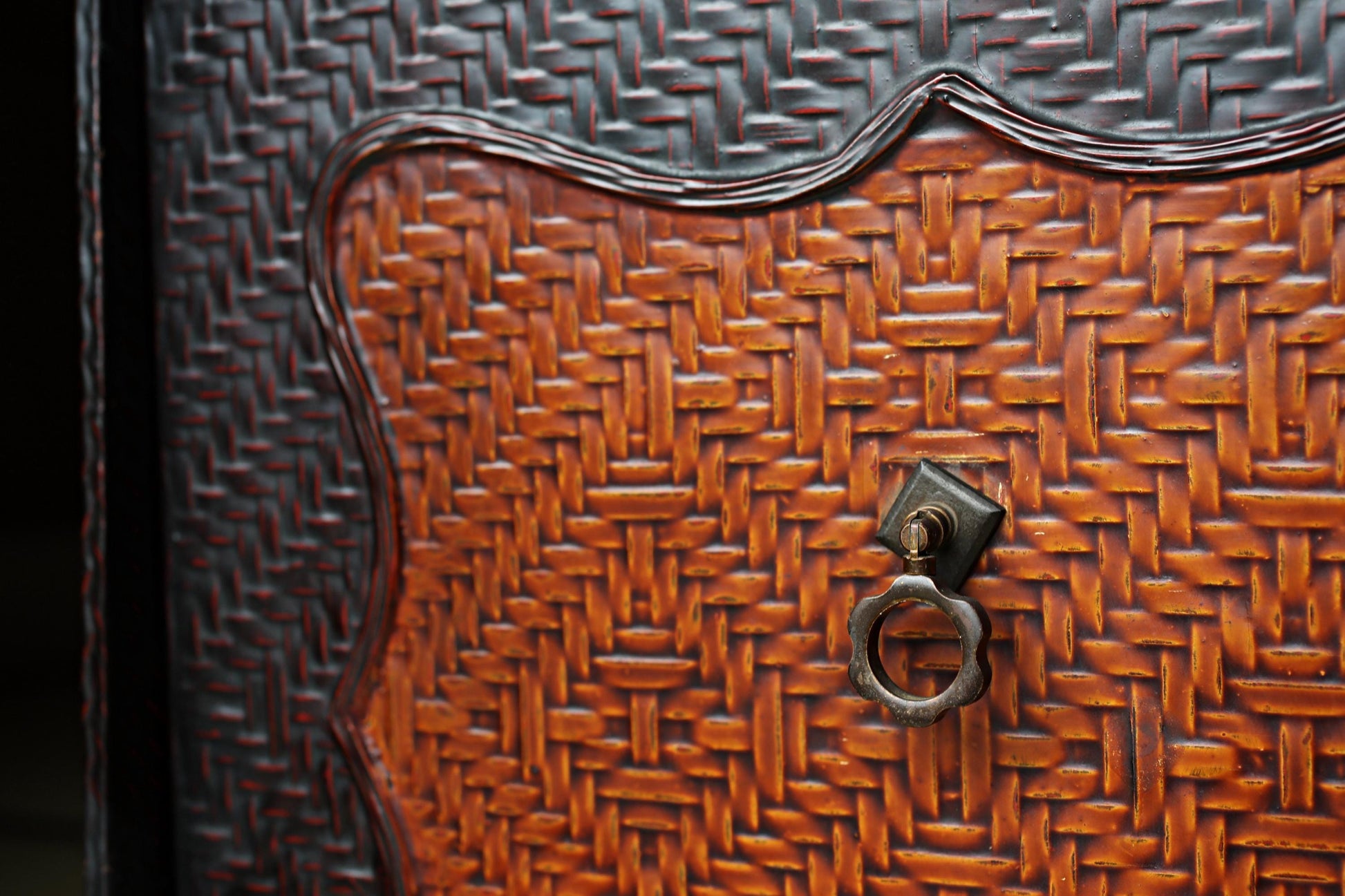 a close-up view of a woven wooden surface with a metal handle attached to it.