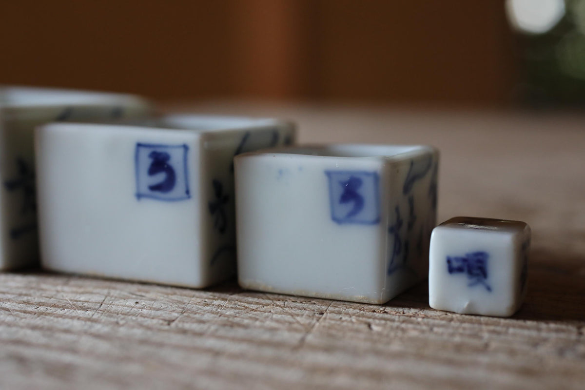 A collection of small white ceramic objects with blue designs, arranged on a wooden surface.
