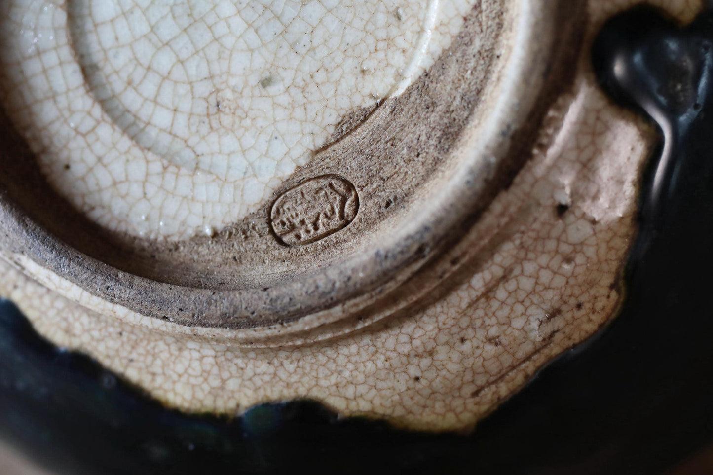 A close-up image of a ceramic bowl or dish with a textured surface, featuring a small engraved mark or logo.