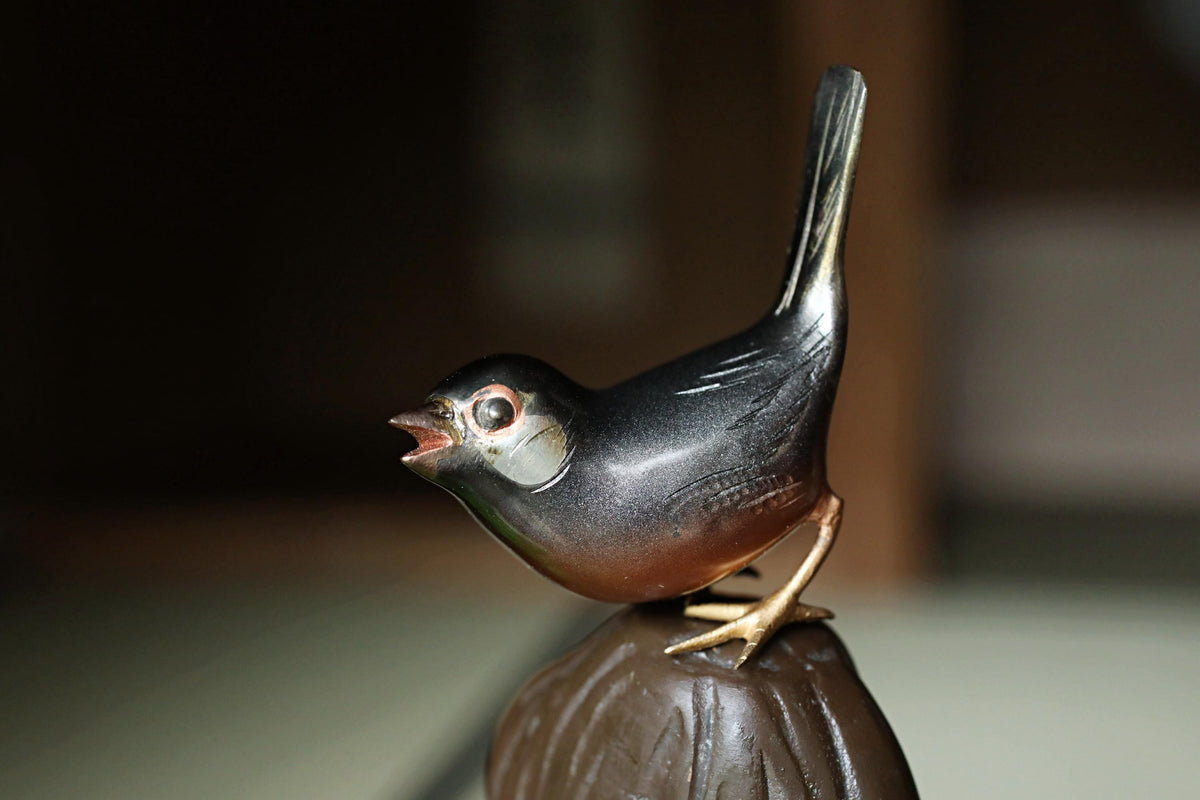 A small, black bird figurine perched on a brown base.