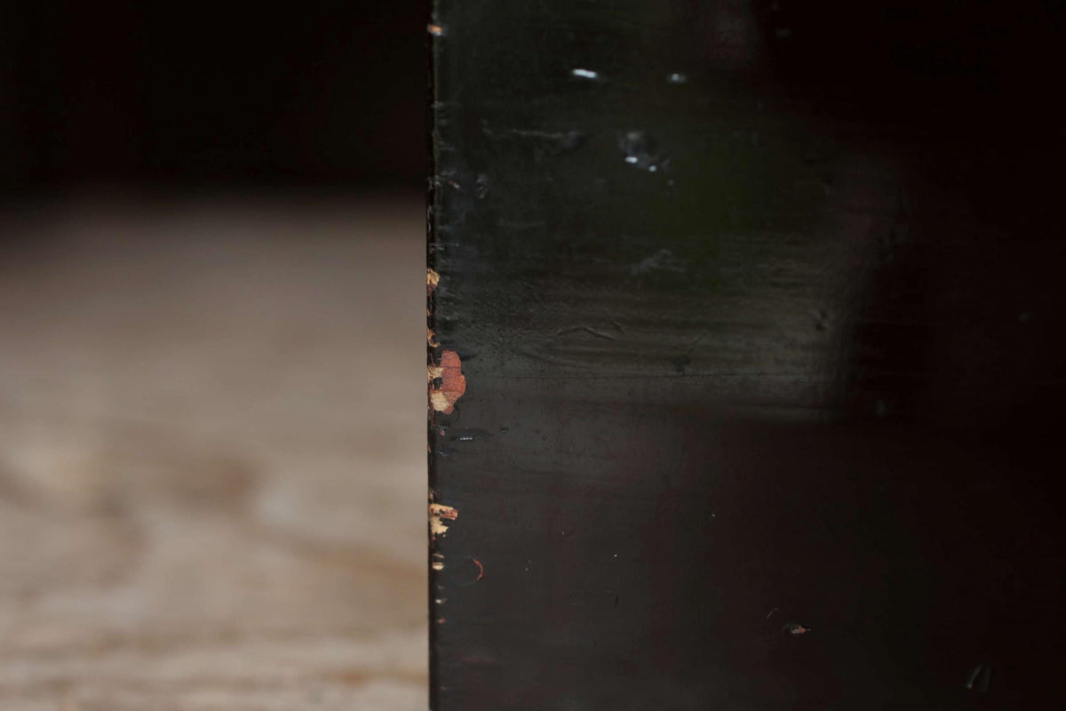 a close-up view of a black surface with some visible wear and tear, including a small chip or scratch on the right side.
