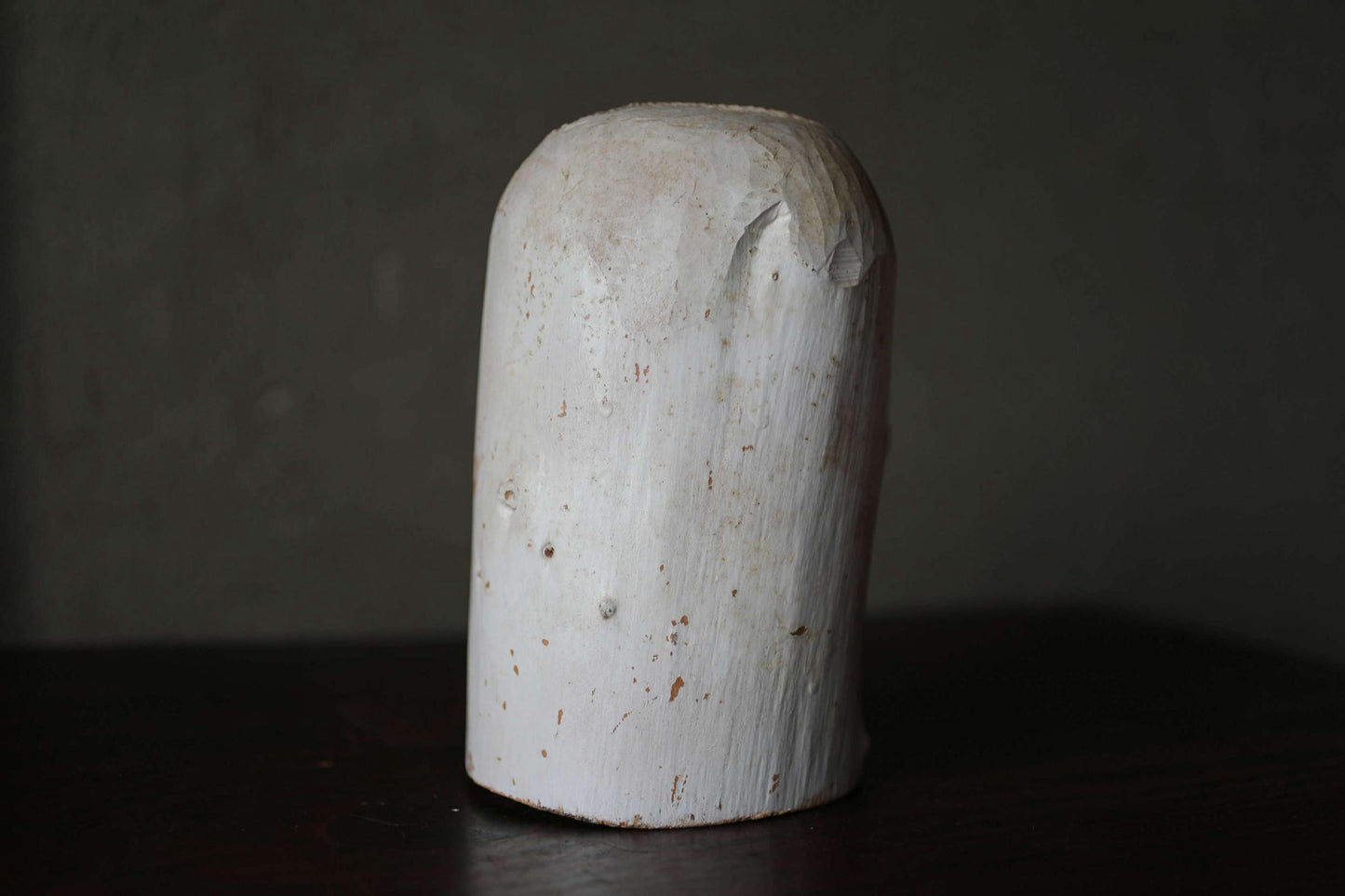 A white, cylindrical object with a rough, textured surface sits on a dark surface.