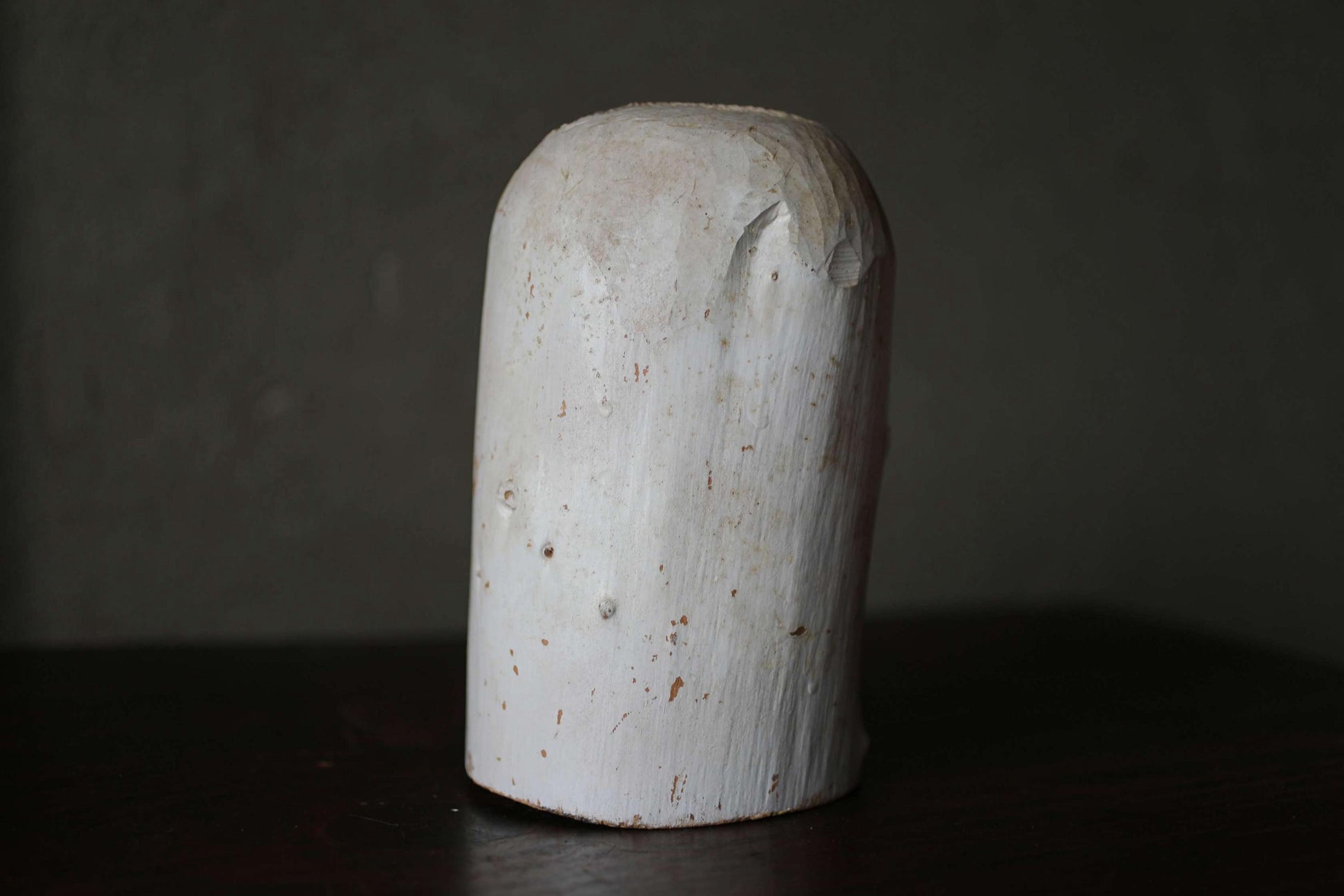 A white, cylindrical object with a rough, textured surface sits on a dark surface.