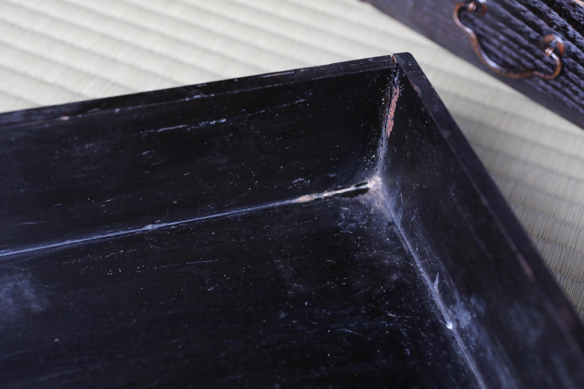 A close-up view of a black, rectangular tray with a visible crack in the corner.