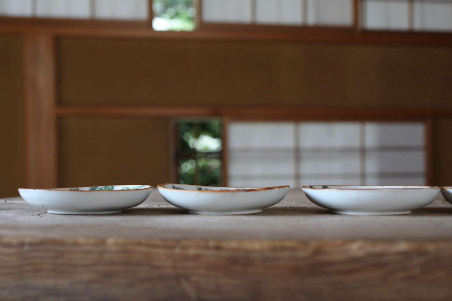 Three white ceramic bowls with intricate designs are arranged in a row on a wooden surface.