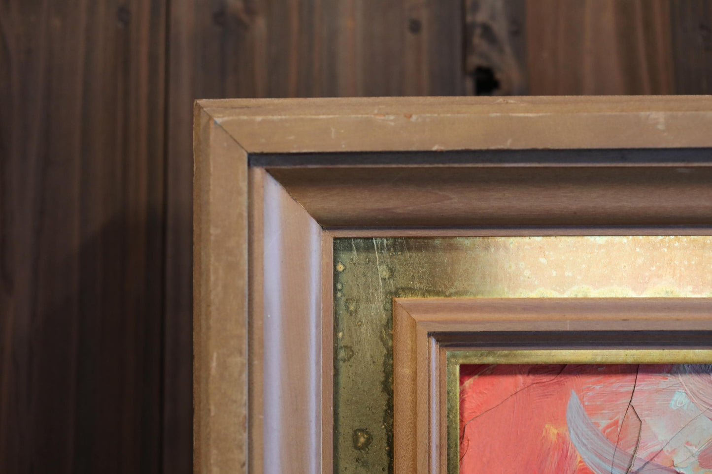 a close-up view of a wooden frame with a painting inside, set against a wooden background.