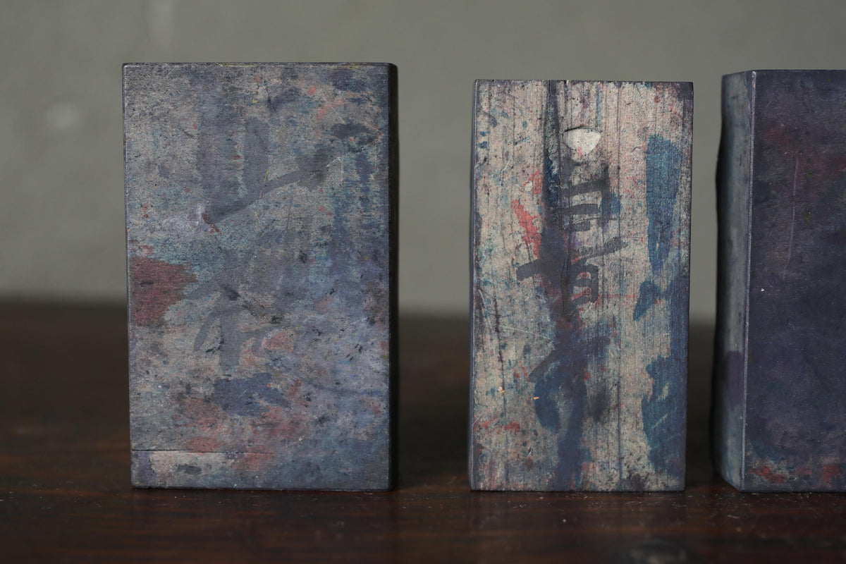 three rectangular metal blocks with varying textures and colors, arranged on a wooden surface.