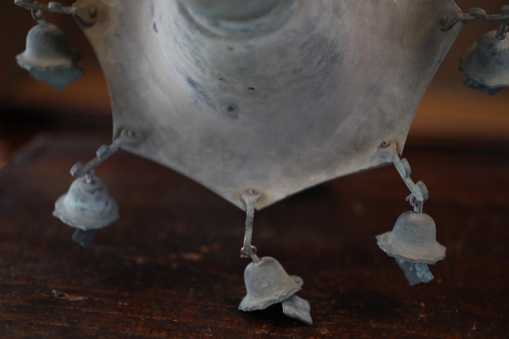 A close-up view of a metal object with several small bells attached to it, hanging from a chain.