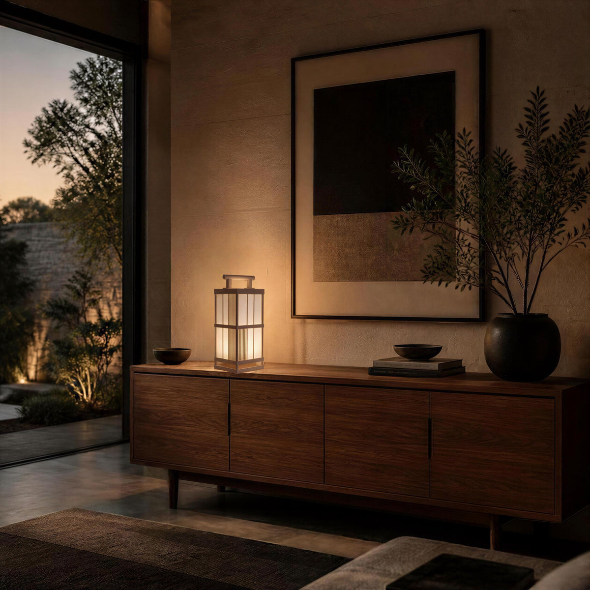 a serene and modern living room with a large window overlooking a garden, a wooden cabinet with a lamp, and a framed artwork on the wall.