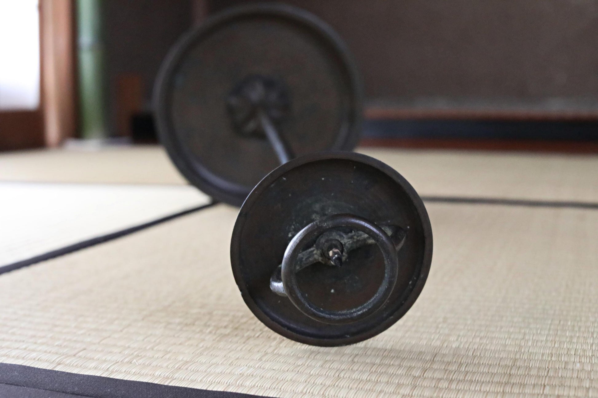 a close-up view of a black metal object, possibly a piece of furniture or a decorative item, resting on a woven mat or mat-like surface.