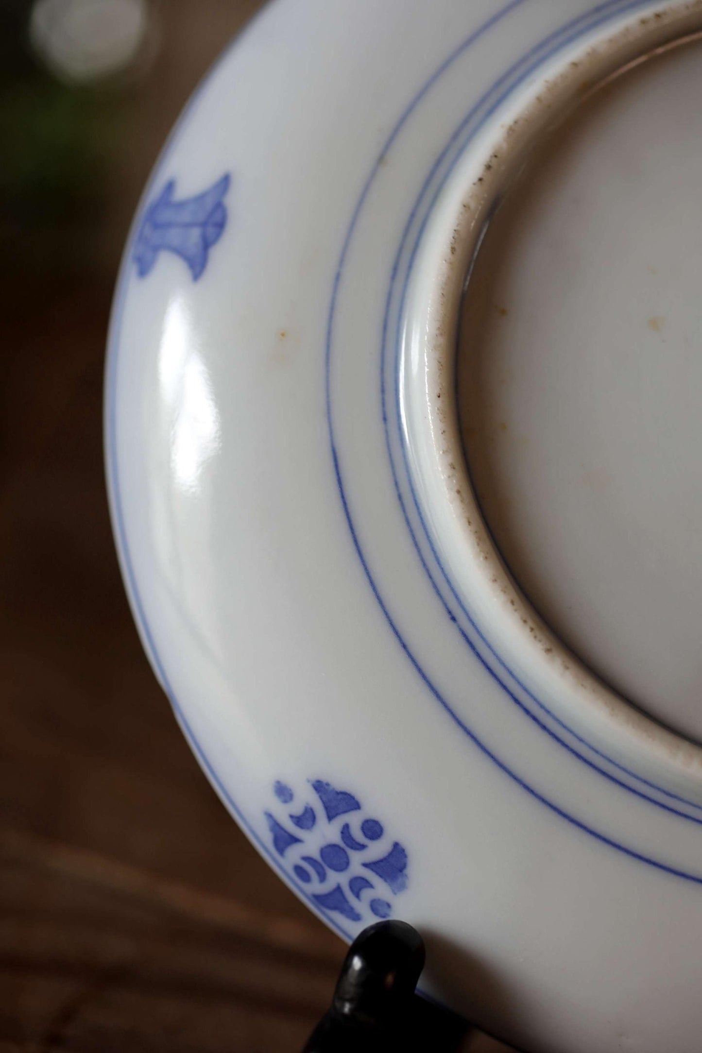 A close-up view of a white ceramic plate with blue decorative patterns, including a small blue flower design.