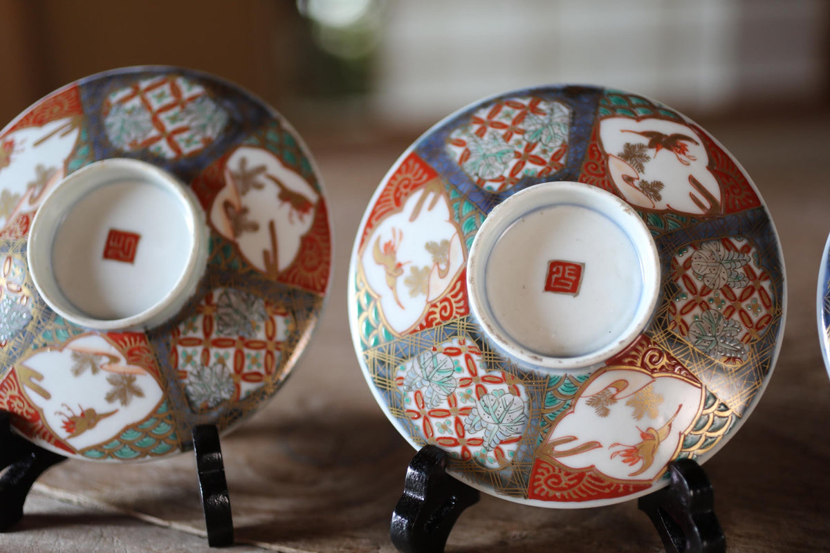 two ornate ceramic cups or saucers with intricate designs and patterns, placed on a wooden surface.