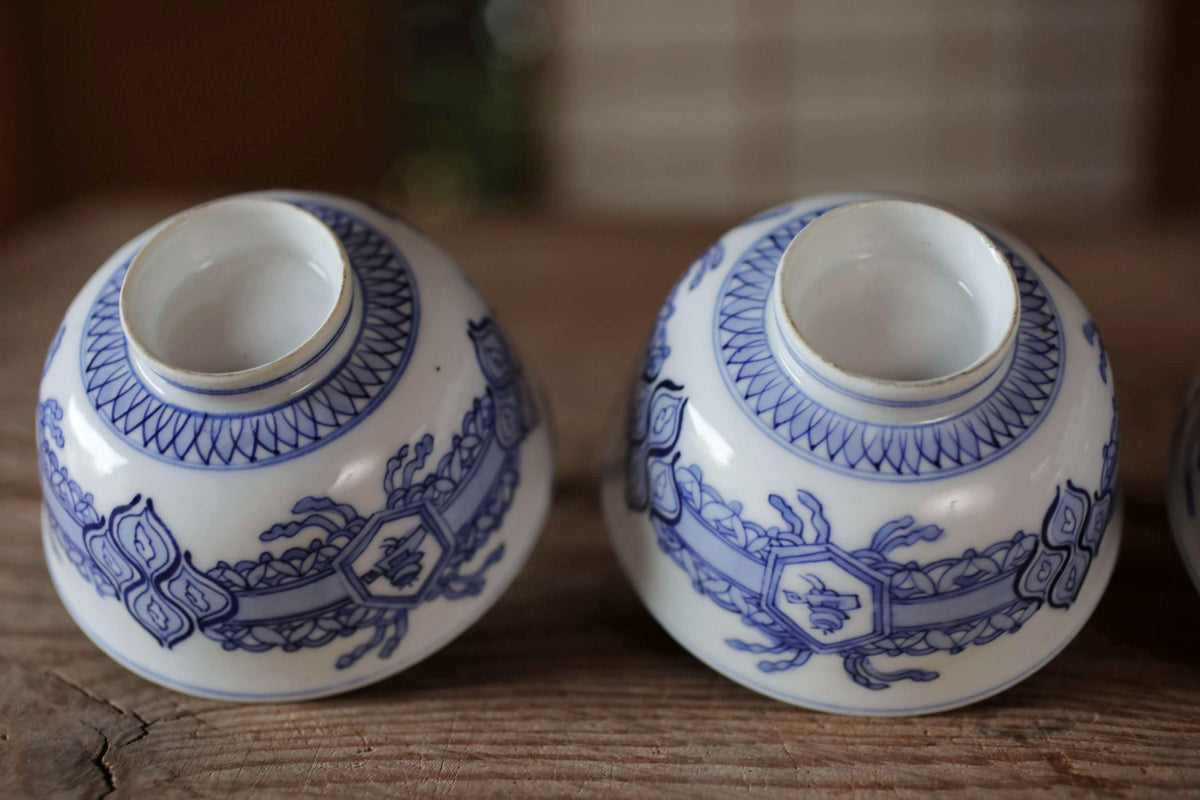two blue and white porcelain bowls with intricate designs, placed on a wooden surface.