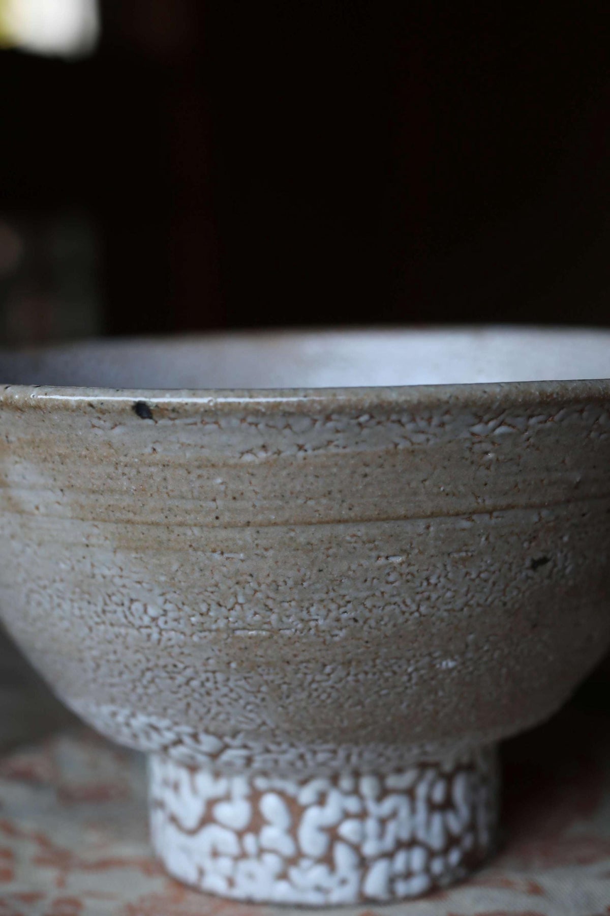 A close-up image of a white ceramic bowl with a textured surface, sitting on a patterned surface.