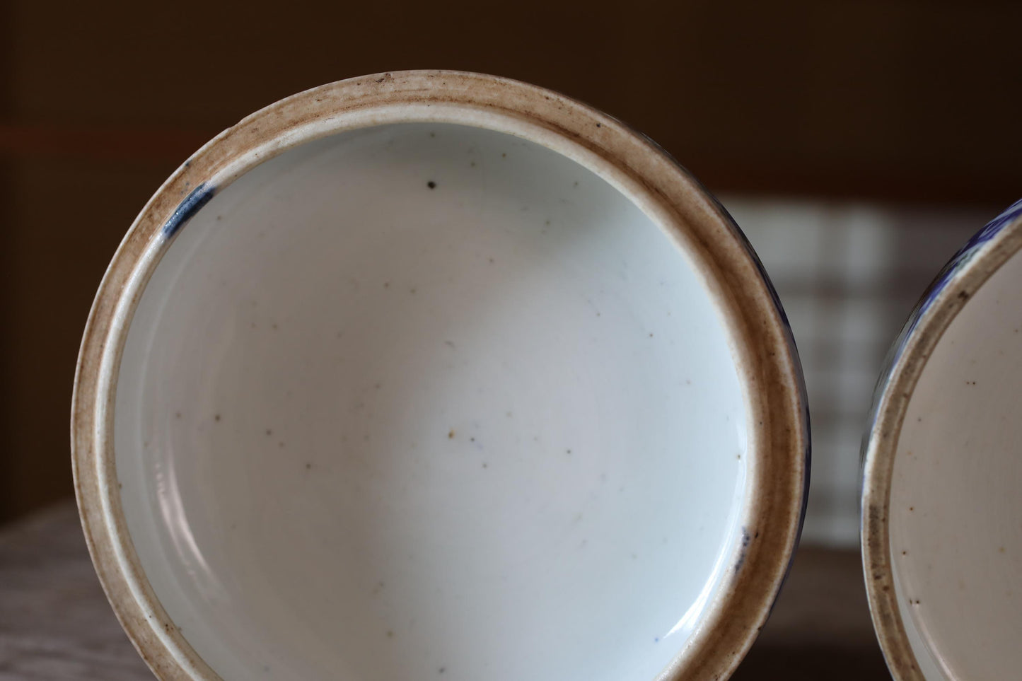 A close-up view of a white ceramic bowl with a blue rim, featuring a few small spots on its surface.
