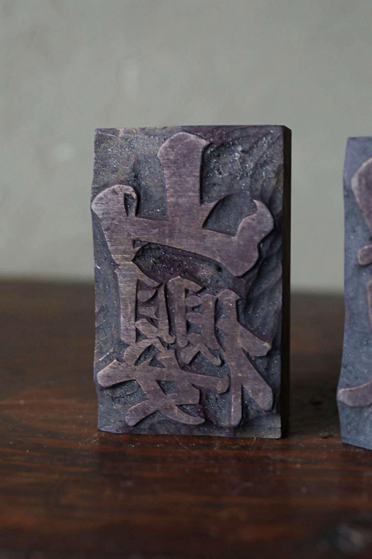a dark-colored rectangular object with an intricate design or carving on it, placed on a wooden surface.