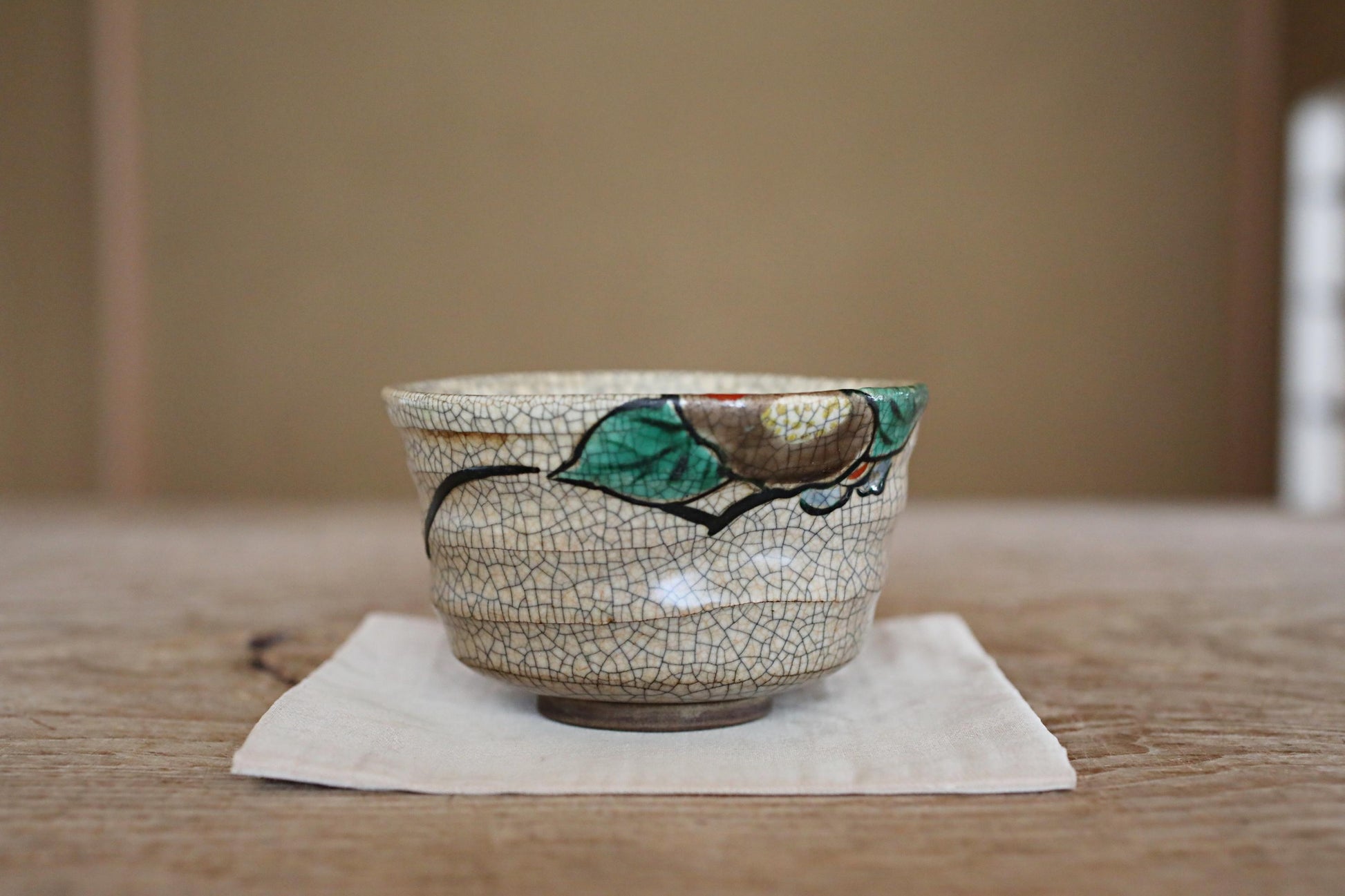 A ceramic bowl with a floral design sits on a white cloth on a wooden surface.
