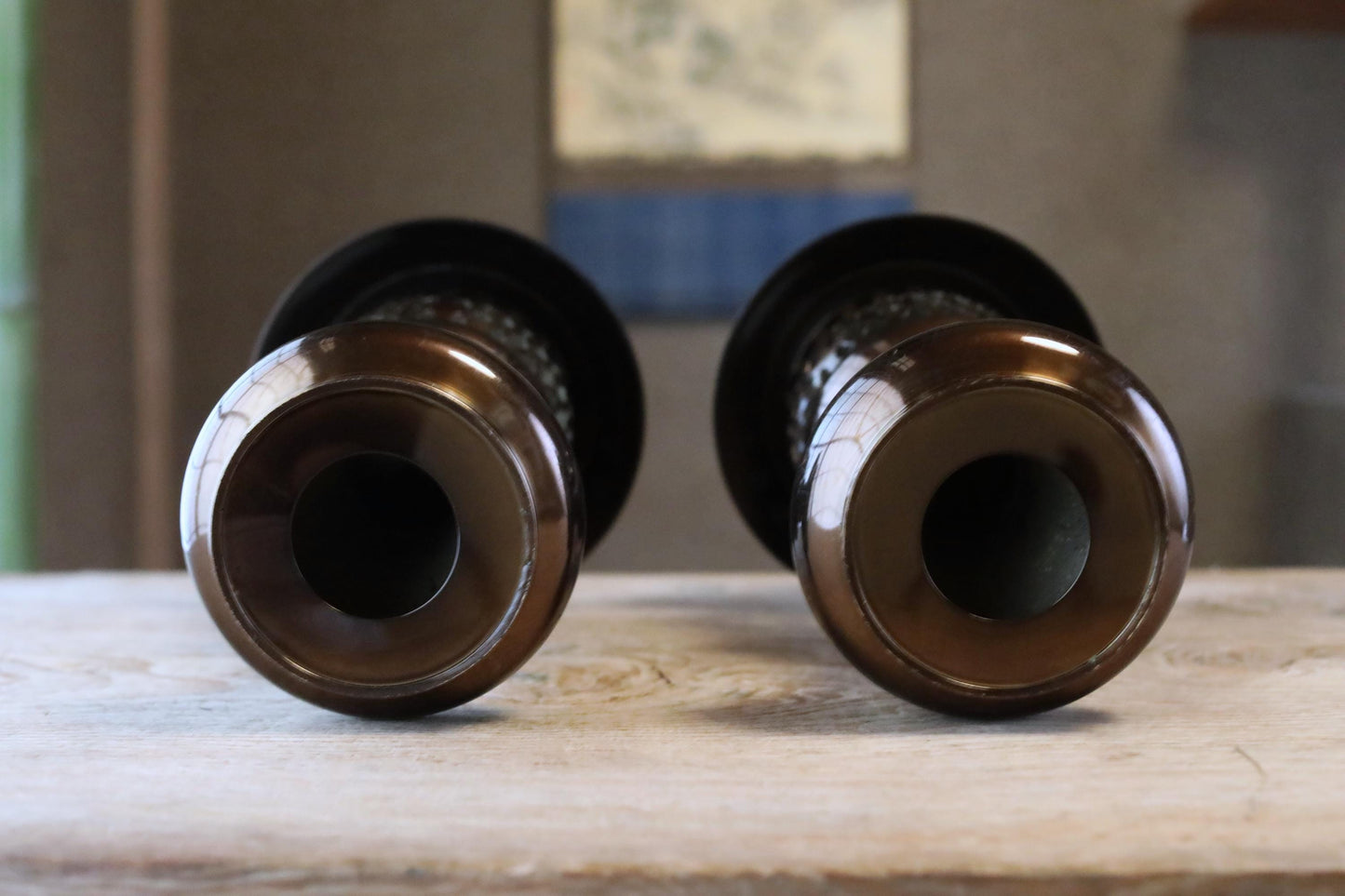 Two brown, cylindrical objects with a textured surface are placed on a wooden surface, facing each other.