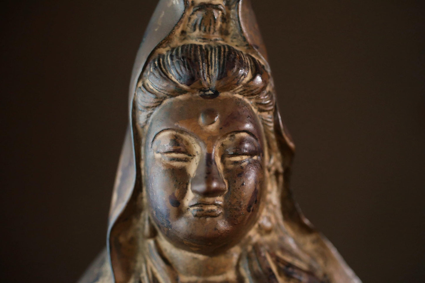 A close-up image of a bronze statue depicting a serene, contemplative figure with a serene expression.
