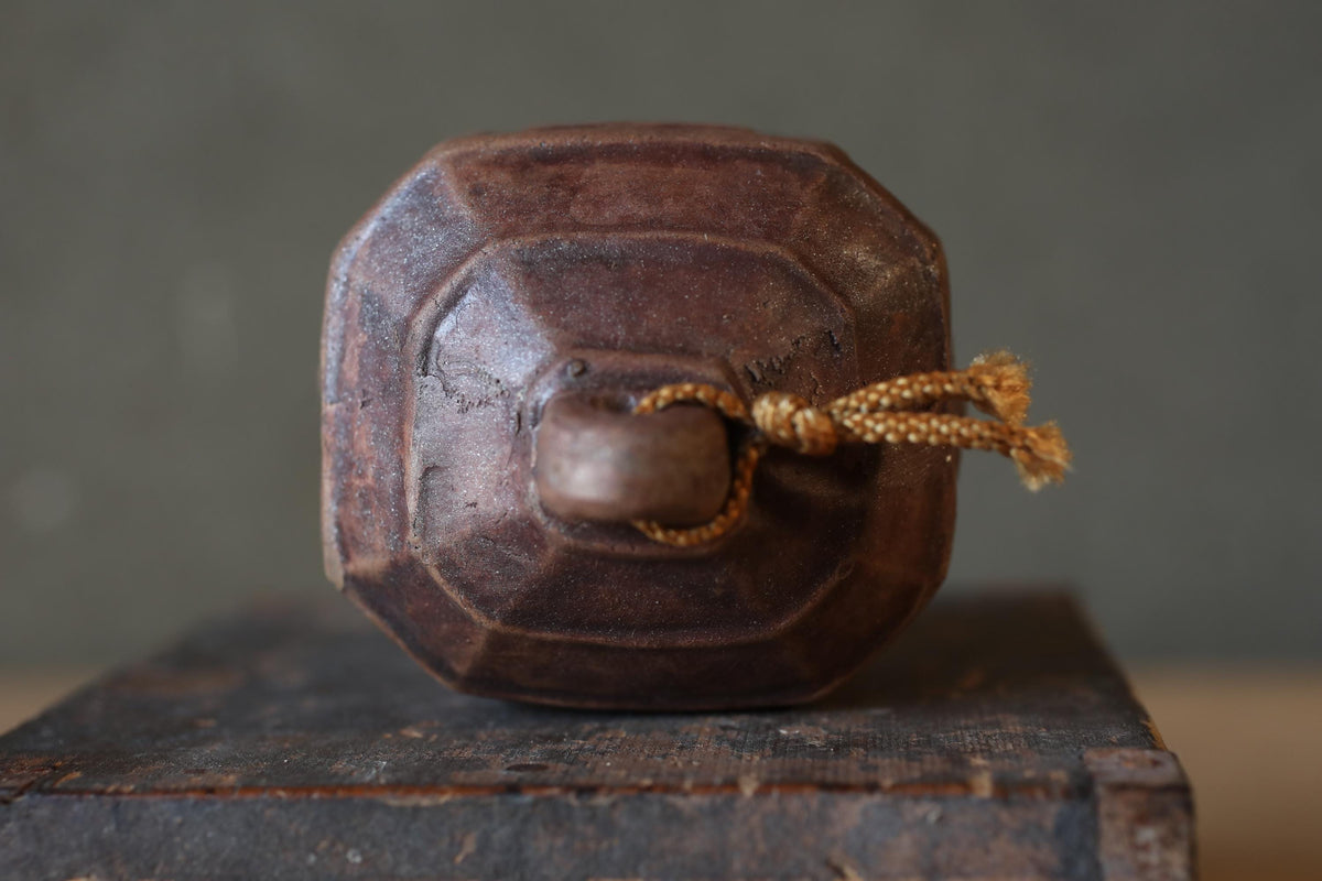 An old, rusted metal object with a curved shape, sitting on a wooden surface.