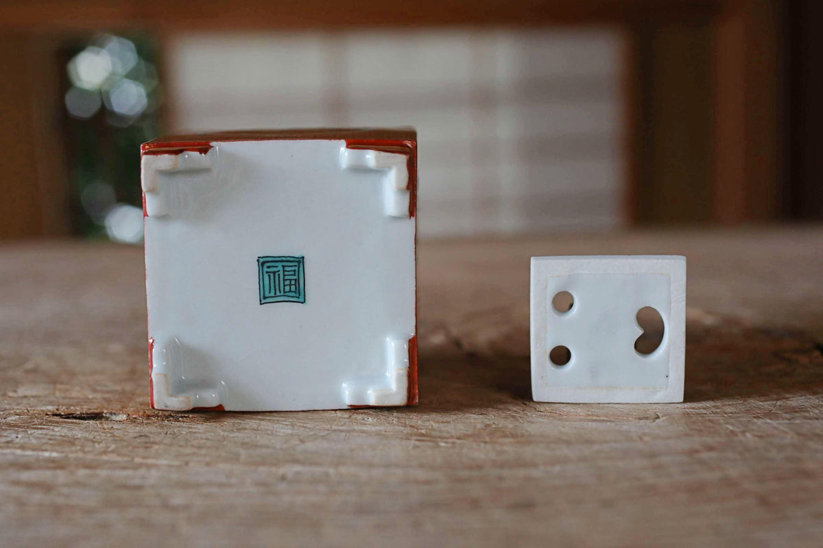 a small white square and a larger red and white square on a wooden surface, with a blurred background.