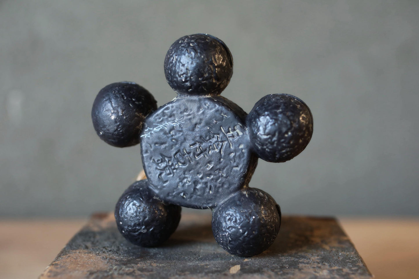 A close-up image of a dark metal sculpture composed of six spheres, arranged in a circular pattern.