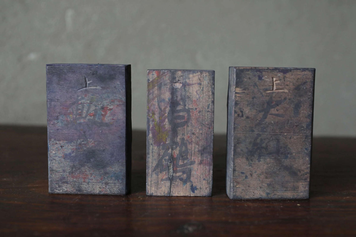 Three wooden blocks with different textures and patterns are arranged on a wooden surface.