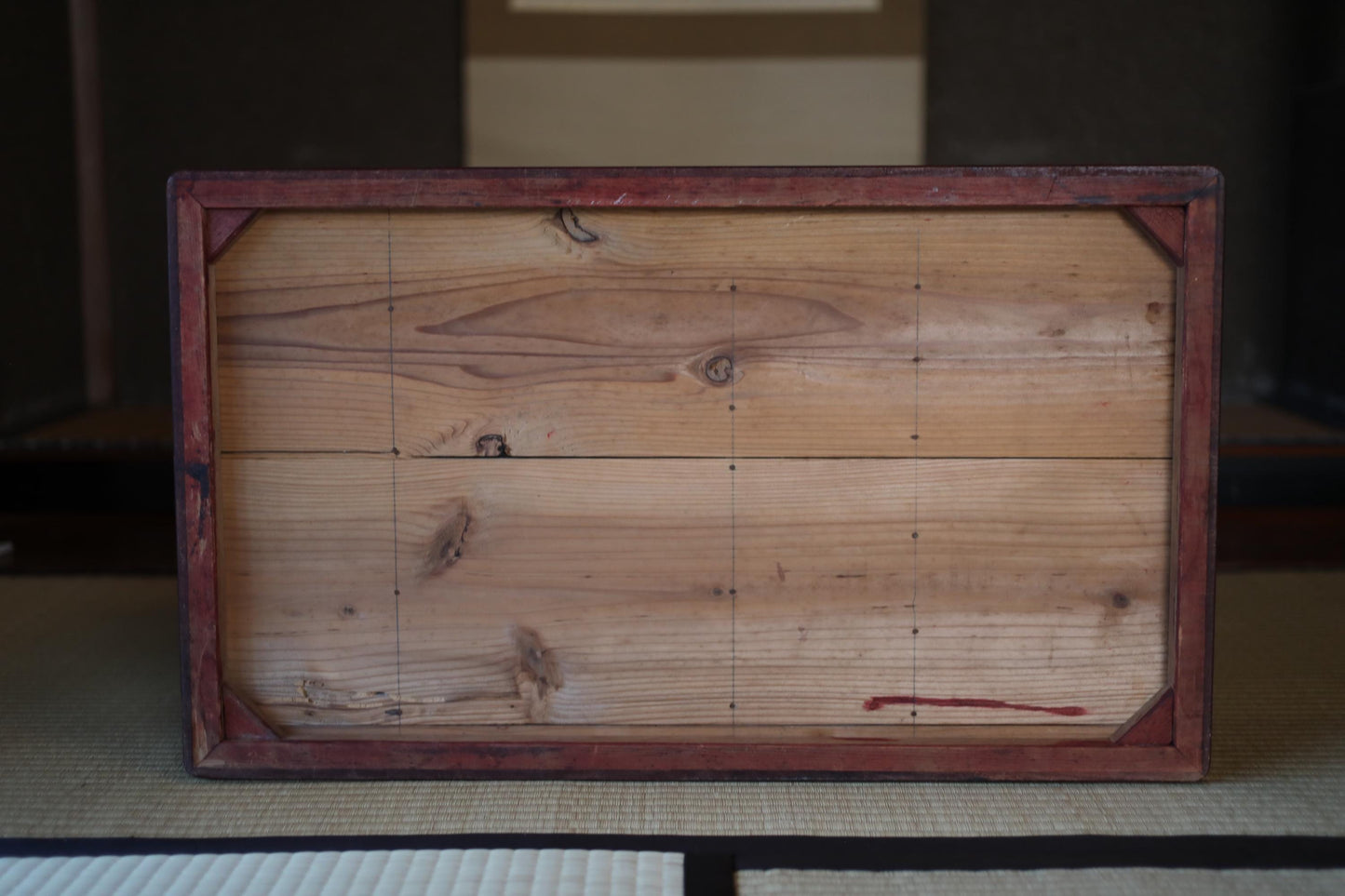 a wooden frame with a red border, placed on a tatami mat.