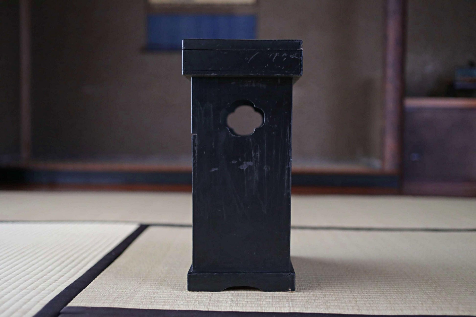 A black wooden object with a circular cutout in the center, placed on a white mat with a wooden frame.