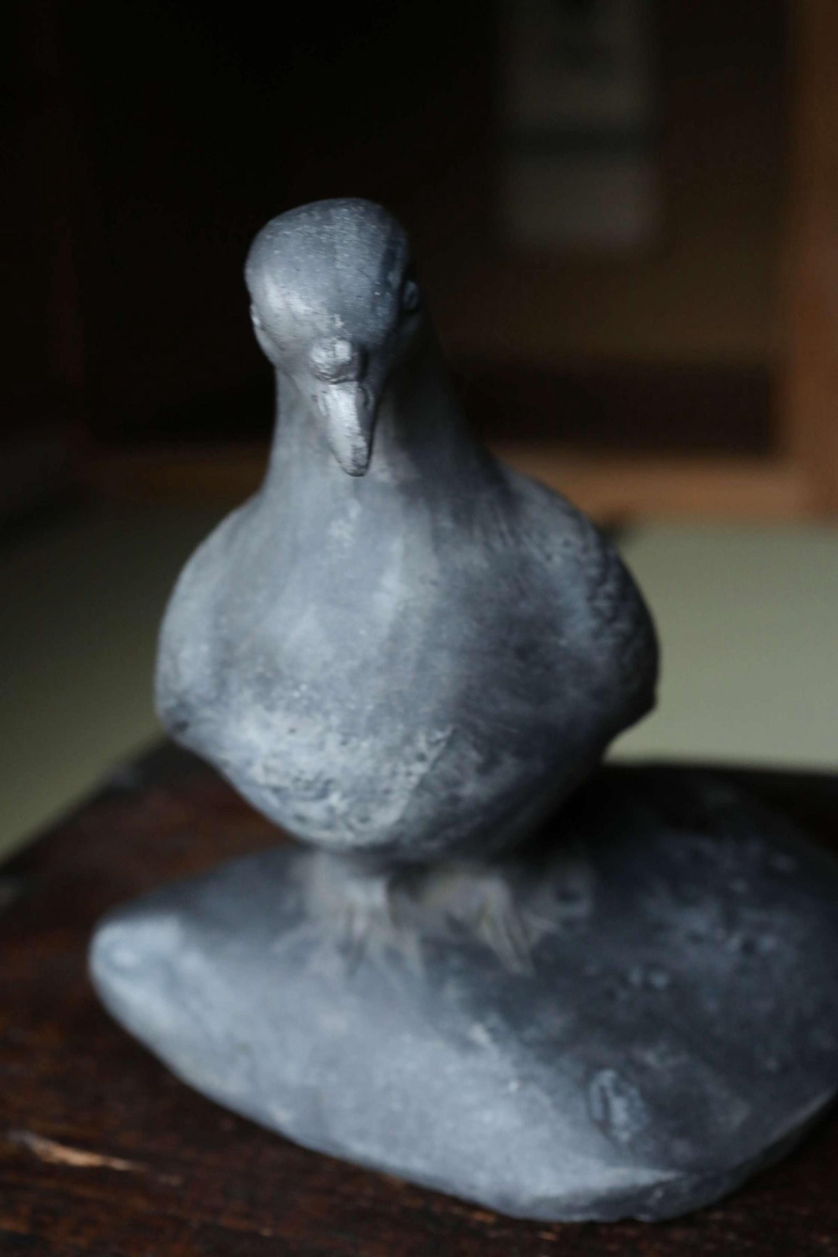 A gray metal bird statue perched on a rock.