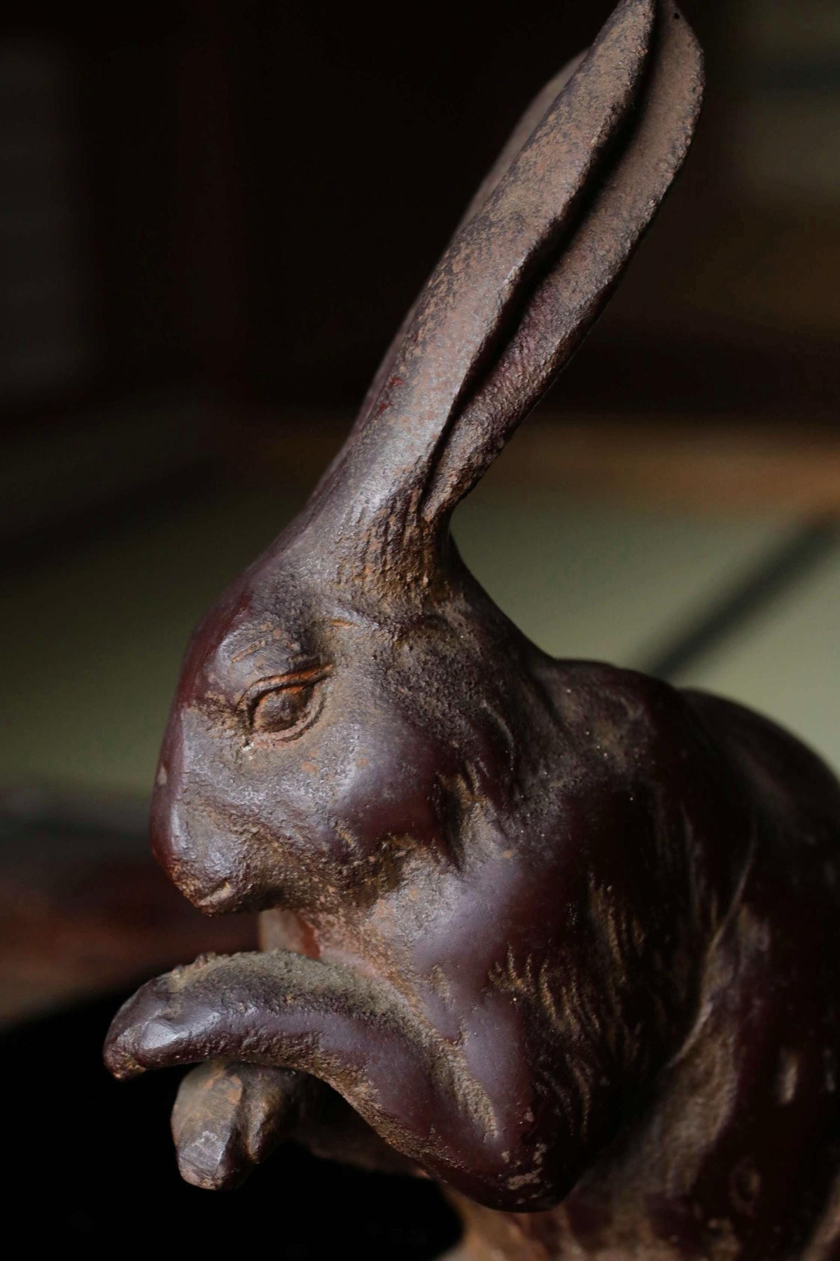 A close-up view of a dark brown, weathered metal sculpture of a rabbit or hare.