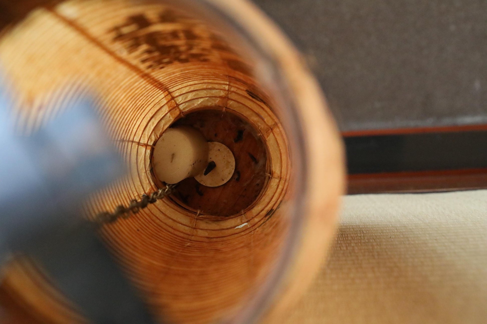 a close-up view of a wooden object, possibly a piece of furniture or a decorative item, with a circular hole in the center. The object appears to be made of wood and has a textured surface.