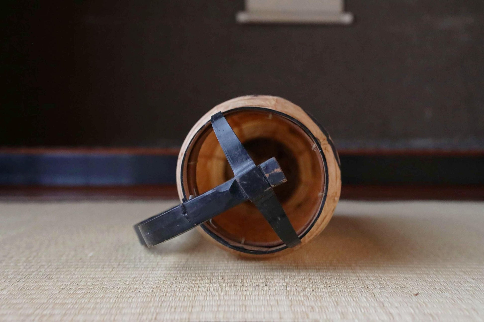 a wooden object with a black metal piece attached to it, resting on a textured surface.