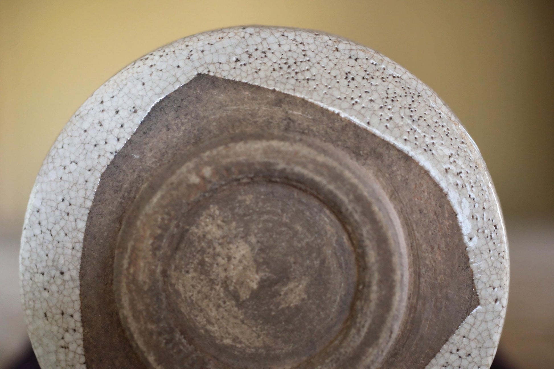 a close-up view of a ceramic or metal object with a textured surface, featuring a combination of white and brown colors.
