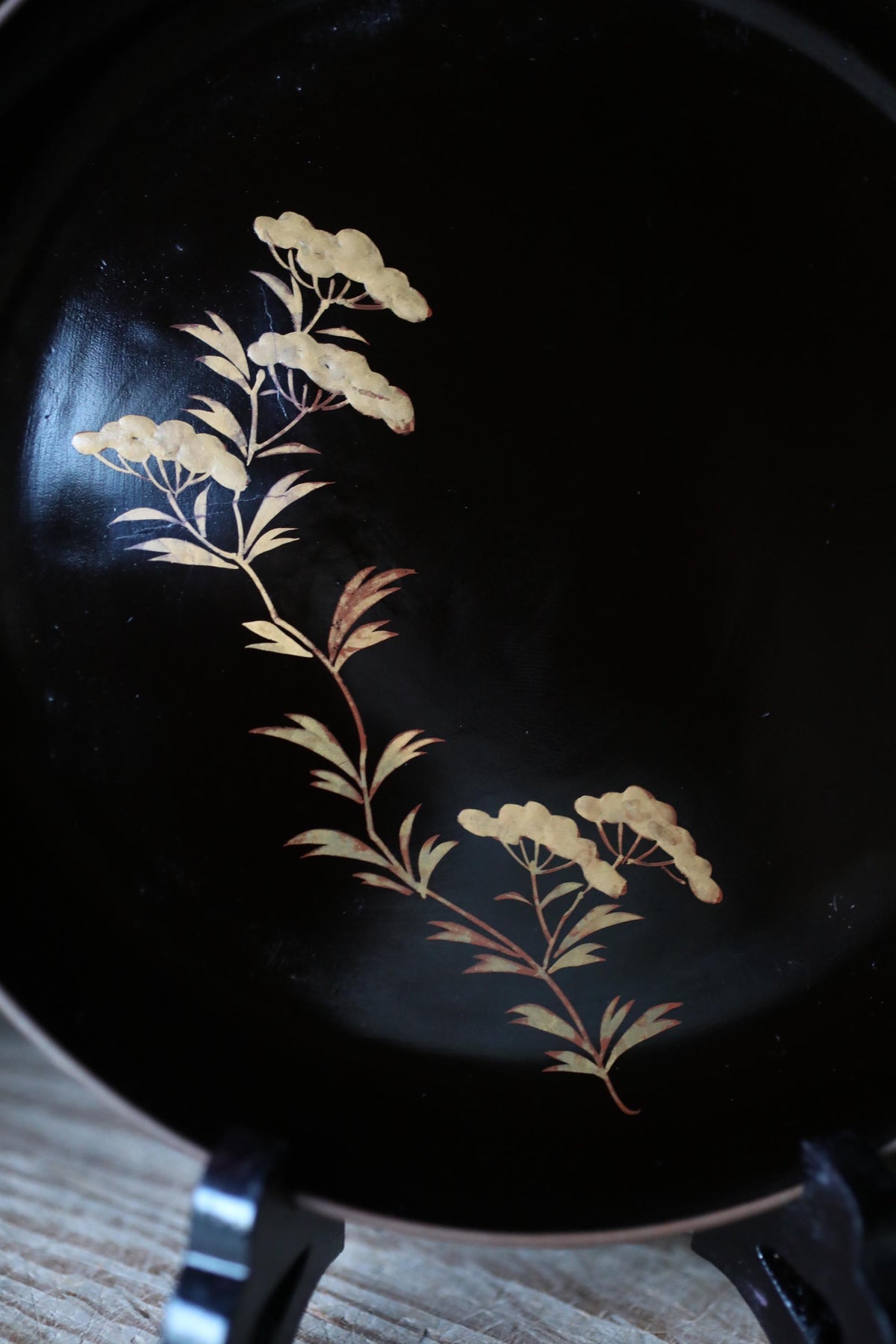 a black plate with a decorative design of white flowers and leaves on it.