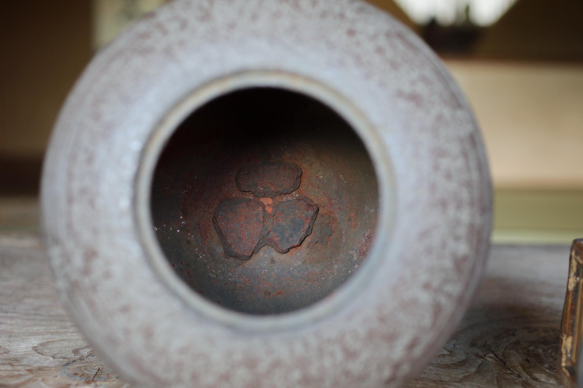 a close-up view of a rusted metal object, possibly a piece of pottery or a metal container, with a hole in the center.