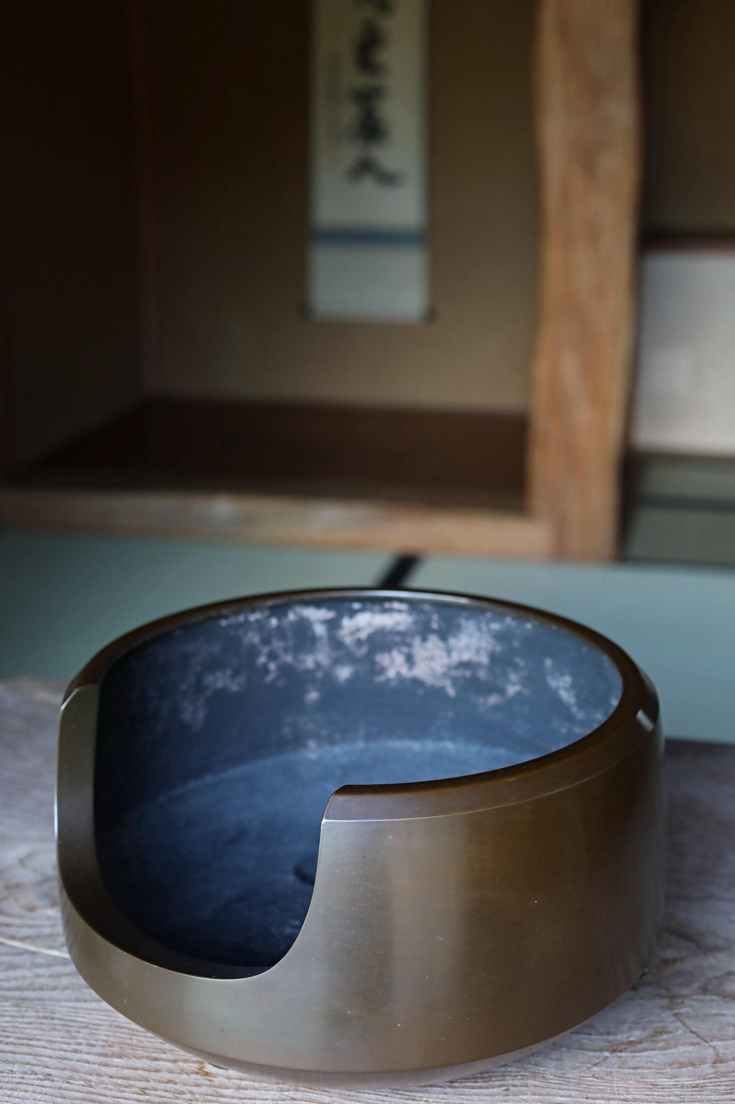 A round, brown ceramic bowl with a blue interior sits on a wooden surface.