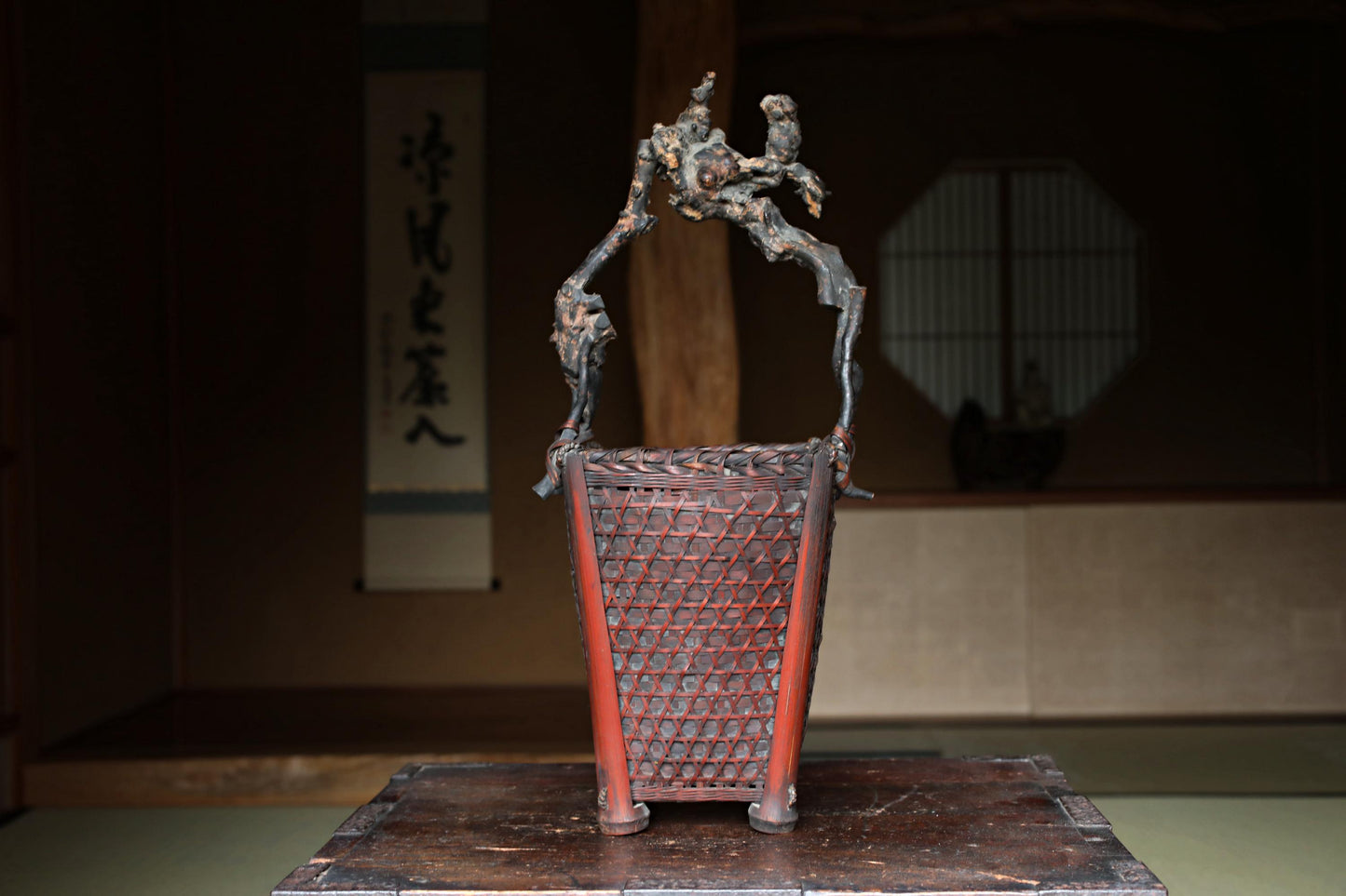a wooden basket with a red handle, placed on a wooden surface.