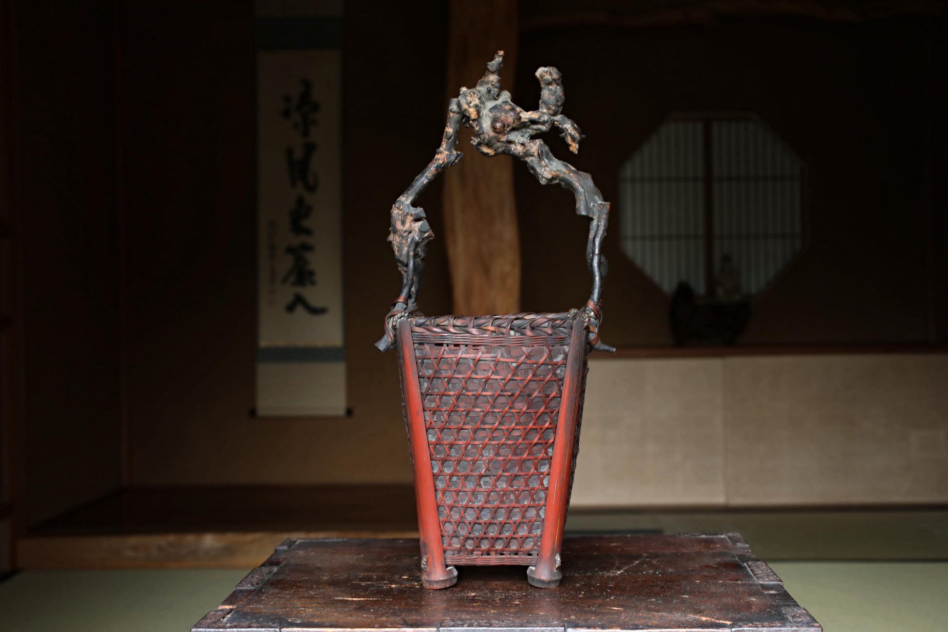 a wooden basket with a red handle, placed on a wooden surface.