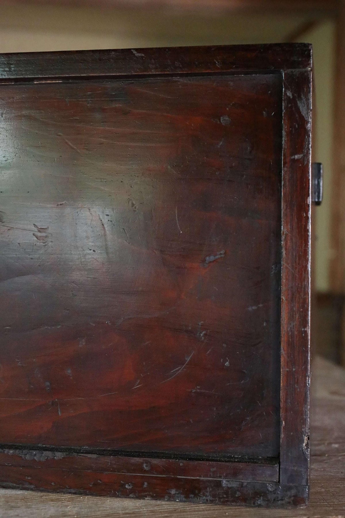 a close-up view of a dark wooden surface, possibly a piece of furniture or a wooden panel.