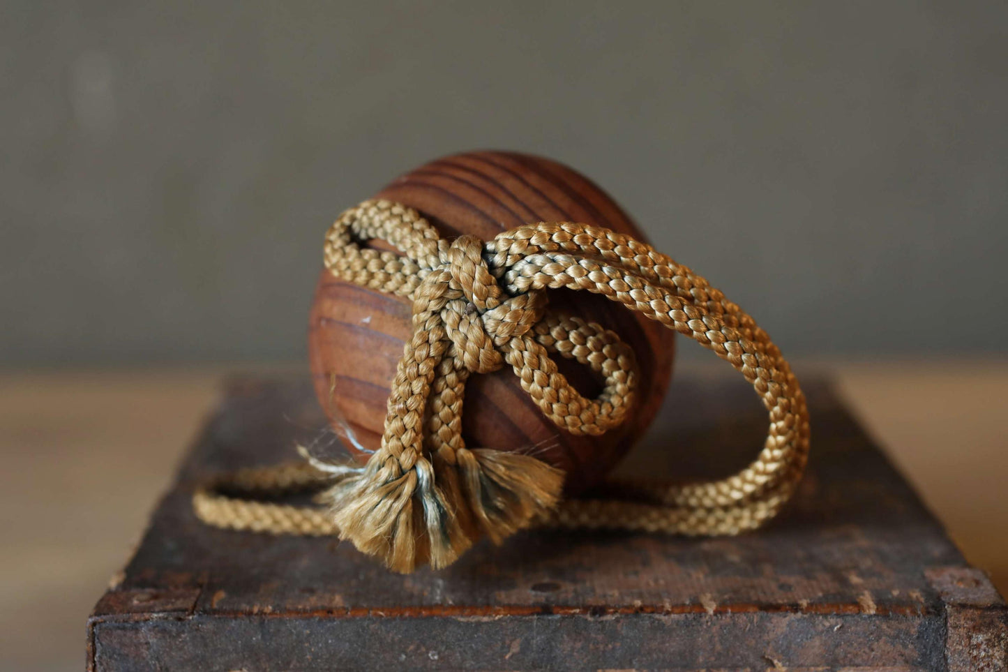 A wooden ball with a rope tied around it, resting on a wooden surface.