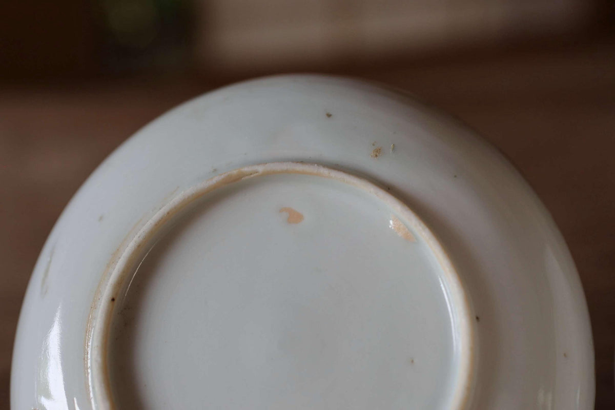 A close-up view of the bottom of a white ceramic plate, showing a small chip or mark on the surface.