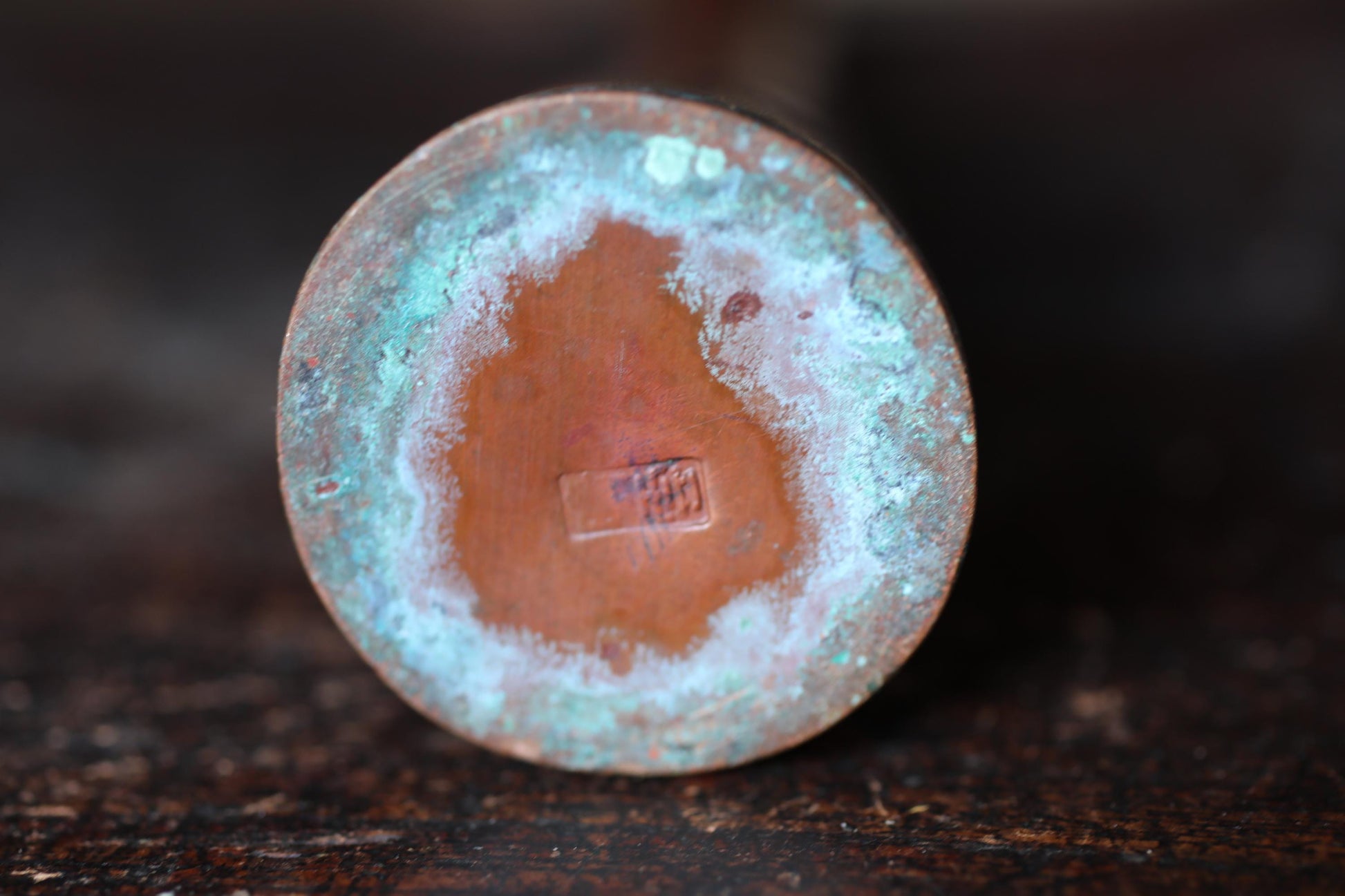 the underside of a round, rusted metal object with a blue and orange color scheme.