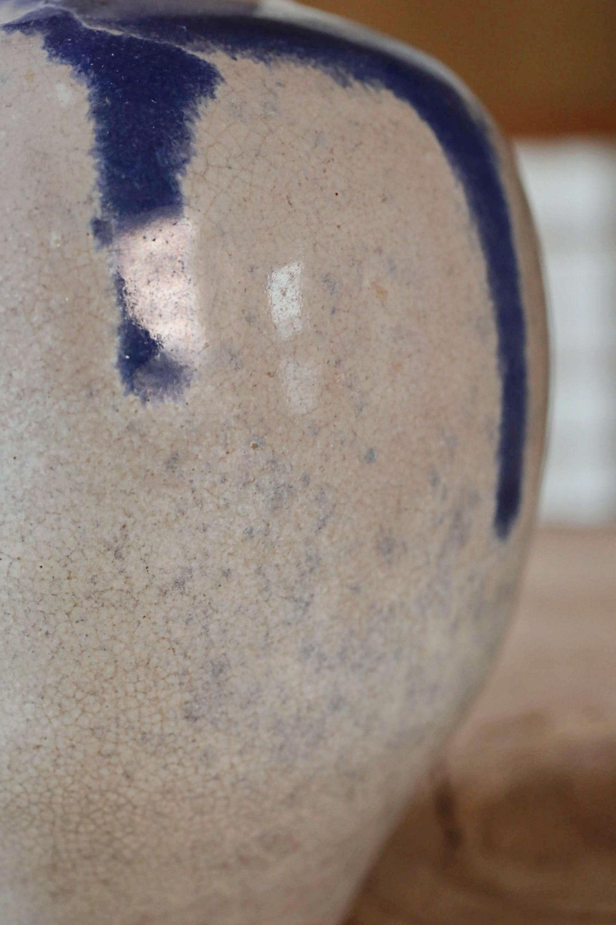 A close-up view of a ceramic vase with a blue stripe running down its side.