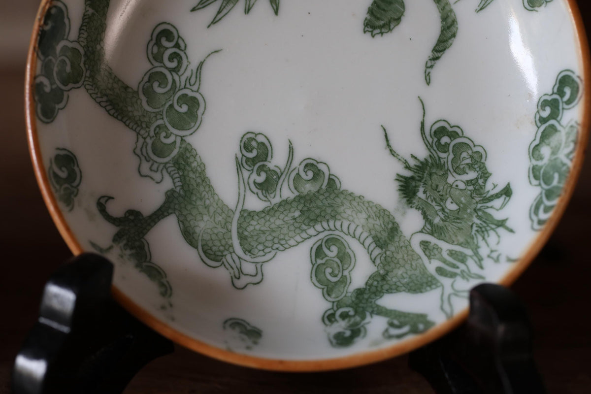 a decorative plate with a dragon design, which is placed on a stand.