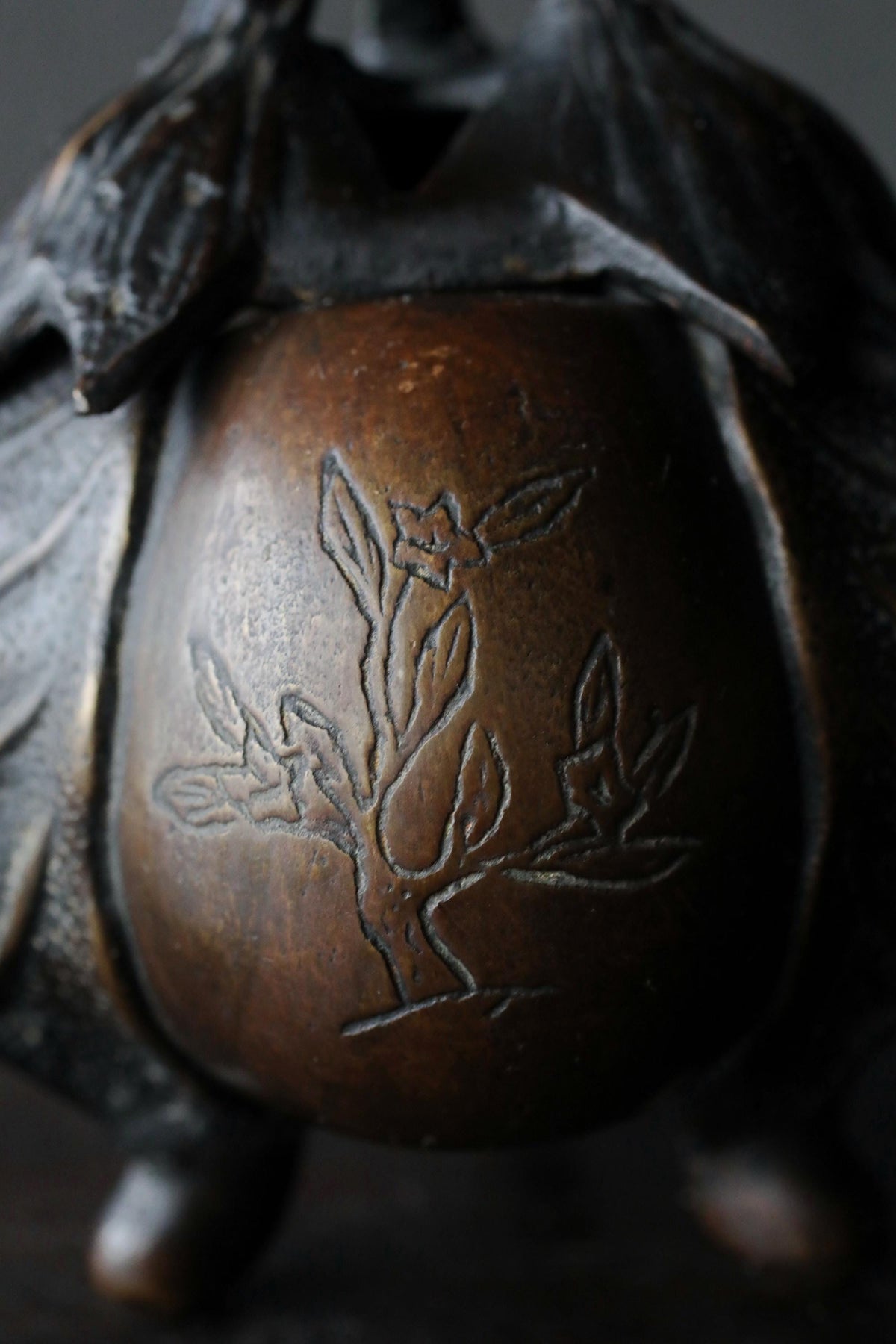 A close-up image of a bronze object with a tree-like design etched onto its surface.