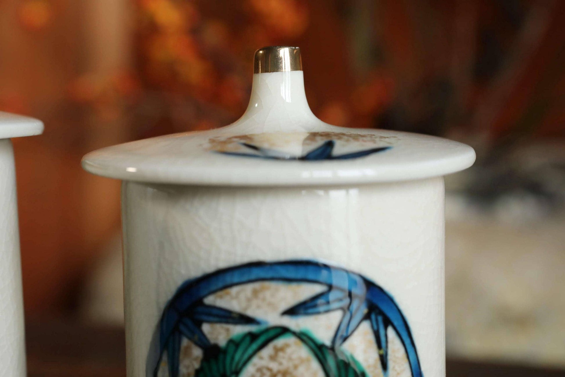 A close-up image of a white ceramic jar or container with a decorative blue and green design on its surface.