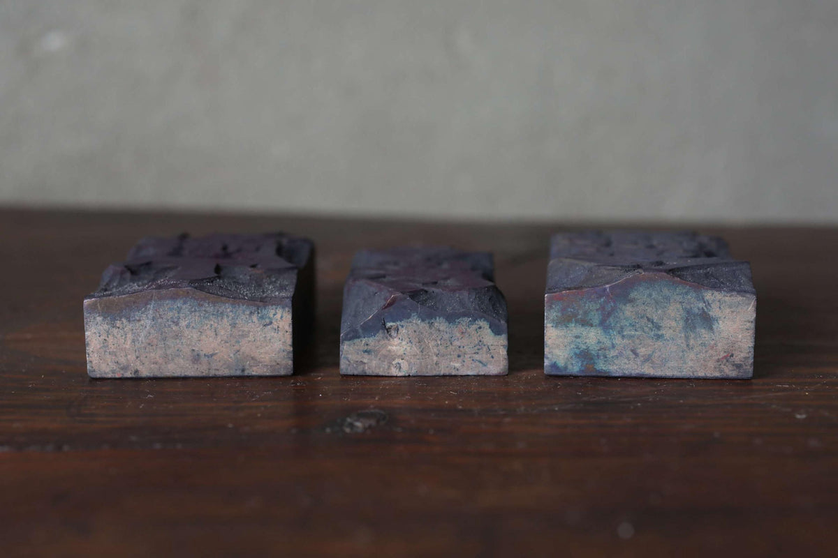 Three dark-colored rectangular objects are arranged on a wooden surface.