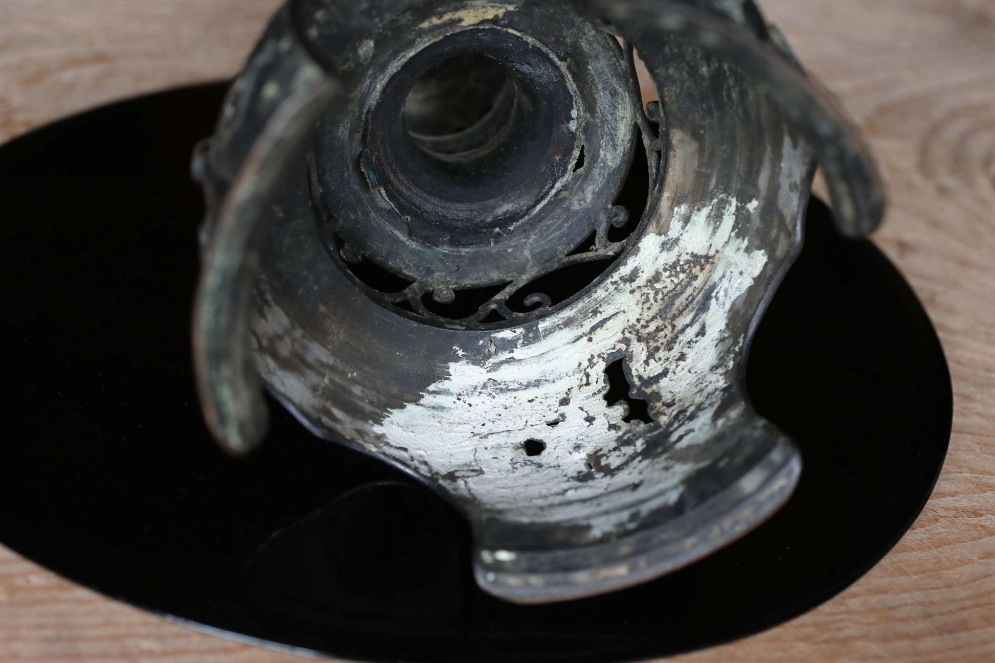 a close-up view of a metal object, possibly a piece of art or a decorative item, with a black background.